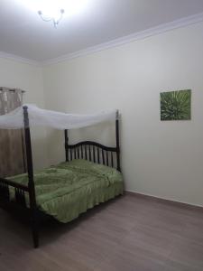 een slaapkamer met een hemelbed bij Freeve Suites Akright City Bwebajja in Buzzi