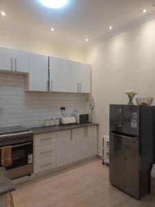 a kitchen with white cabinets and a stainless steel refrigerator at Freeve Suites Akright City Bwebajja in Buzzi
