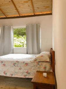 a bedroom with a bed and a window with a table at Apto 1030 in Trancoso