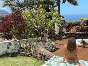 a woman sitting on a towel in a garden at Casa Las Colinas- Preciosa Villa Isleña in La Orotava