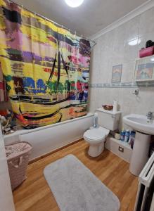 een badkamer met een toilet, een wastafel en een douchegordijn bij Spacious flat near central in Londen