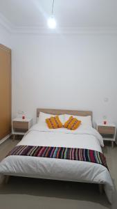 a white bed with two pillows on top of it at Bel Appart Marina Golf Asilah in Asilah