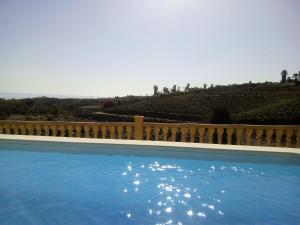 a blue swimming pool with a fence and a hill at Casa rural CAÑADA PAEZ in Vélez-Málaga