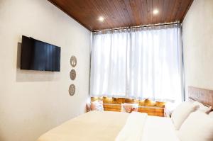 a bedroom with a bed and a tv and a window at Vista do Vale lofts - Itaipava in Petrópolis