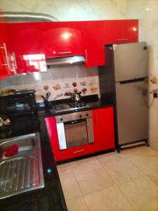cocina con armarios rojos y nevera de acero inoxidable en Résidence alhouda en Agadir