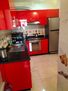 a kitchen with red cabinets and a stove top oven at Résidence alhouda in Agadir
