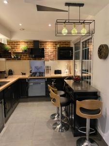 a kitchen with a black counter and chairs in it at Maison Lyon-Bron Eurexpo - Stadium Groupama in Bron