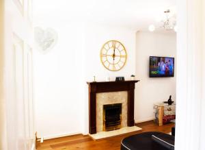 a living room with a fireplace and a clock on the wall at Spacious 4 Bed Home in Milton Keynes -free parking in Milton Keynes