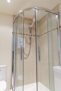 a glass shower in a bathroom with a toilet at Detached Cotswold Stone Coach House in Cheltenham