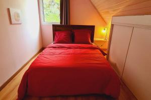 un letto rosso in una piccola stanza con finestra di L'escapade sauvage a Saint-Joseph