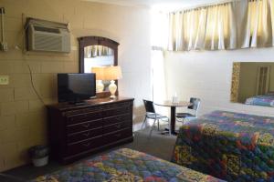 1 dormitorio con 2 camas, TV y mesa en Imperial Motel, en Odessa