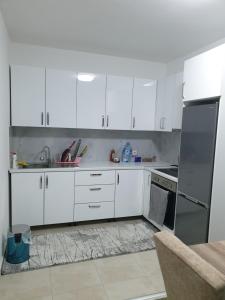 cocina con armarios blancos, fregadero y fogones en Budget Stay Guest House, en Kosovo Polje