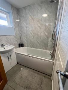 uma casa de banho com uma banheira branca e um lavatório. em Cosy one bed apartment in Carnlough em Ballymena