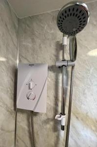 a shower head and a hair dryer on a wall at Cosy one bed apartment in Carnlough in Ballymena