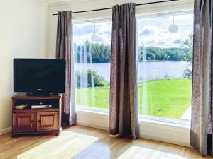 a living room with a television and a large window at Holiday home GUSTAVSFORS in Gustavsfors