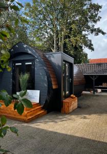 a small black tiny house sitting in a yard at Bijzonder Lekker overnachten in Beetsterzwaag
