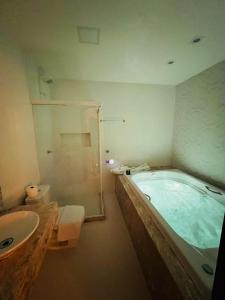 uma casa de banho com uma banheira, um chuveiro e um lavatório. em Pousada Timoneiro em Vila Velha