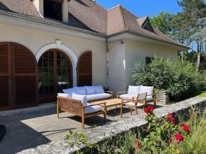 eine Terrasse mit Stühlen, einem Tisch und einem Haus in der Unterkunft Belle demeure de 500m2 avec 6 chambres in Auffreville-Brasseuil