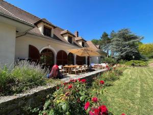 ein Haus mit einem Tisch und einem Sonnenschirm im Hof in der Unterkunft Belle demeure de 500m2 avec 6 chambres in Auffreville-Brasseuil