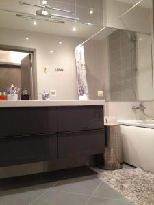 een badkamer met een grote spiegel, een bad en een wastafel bij Liesmas in Rīga