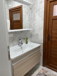 La salle de bains est pourvue d'un lavabo blanc et d'un miroir. dans l'établissement Yeşil ve huzur dolu bir daire, à Bulancak