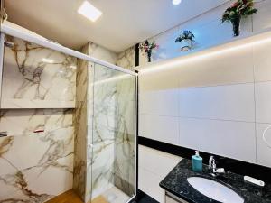 a bathroom with a glass shower and a sink at Praia Dourada in Vila Velha
