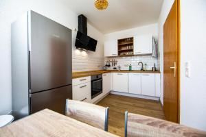eine Küche mit weißen Schränken und einem Kühlschrank aus Edelstahl in der Unterkunft Stadtperle am plätschernden Wasser - 50m2 Zweiraumwohnung in zentraler Lage in Erfurt