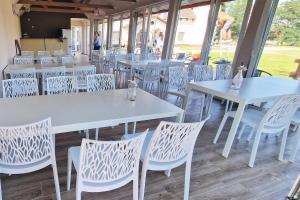 a restaurant with white tables and white chairs at The Luxo Wine Museum Hotel in Kaba