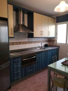 uma cozinha com armários azuis, uma mesa e um lavatório em Fantástico apartamento con vistas en Almerimar em Almerimar