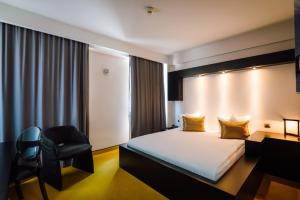 a hotel room with a bed and a chair at Plaza V Hotel in Târgu-Mureş