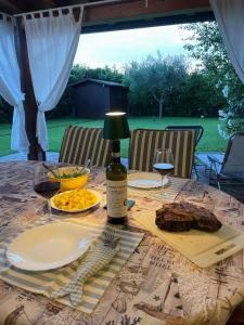 a table with a bottle of wine and a plate of food at Villa con porticato sul prato in Isola Albarella