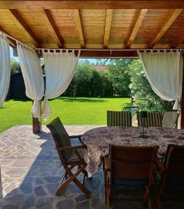 a patio with a table and chairs under a roof at Villa con porticato sul prato in Isola Albarella