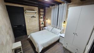 ein kleines Schlafzimmer mit einem weißen Bett und einem Fenster in der Unterkunft Carmit Place in Haifa
