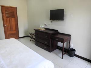 a bedroom with a bed and a dresser with a flat screen tv at The Toucan Inn in Independence