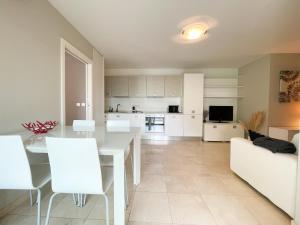 uma cozinha e sala de estar com uma mesa branca e cadeiras em Deux pièces, parking et piscine em Beausoleil