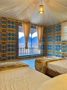 a bedroom with two beds and a large window at Rum Under The Stars Camp in Wadi Rum