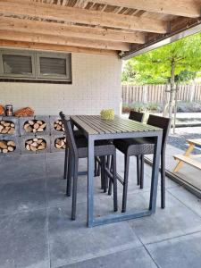 una mesa de madera y sillas en un patio en Family Wellness lodge 4 personen Zuid-Holland!, en Ooltgensplaat