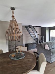 a living room with a wooden table and a chandelier at Family Wellness lodge 4 personen Zuid-Holland! in Ooltgensplaat