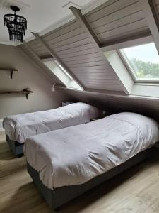 twee bedden in een kamer met een zolder bij Family Wellness lodge 4 personen Zuid-Holland! in Ooltgensplaat