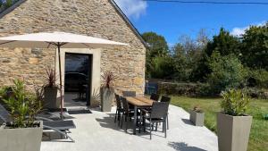 a patio with an umbrella and a table and chairs at Maison bretonne - cottage in Lézardrieux