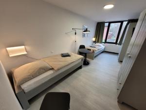 een slaapkamer met 2 bedden en een bureau. bij Guesthouse WI rooms in Jülich