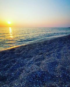 B&B Villa Mariotta في أمانتيا: شاطئ مع غروب الشمس على الماء
