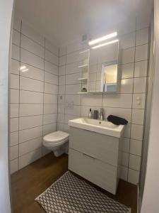 La salle de bains blanche est pourvue d'un lavabo et de toilettes. dans l'établissement Chaleureux studio entre Neuchatel et Bienne, à Le Landeron