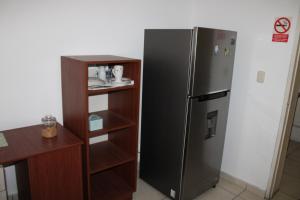 a kitchen with a black refrigerator next to a book shelf at Hospedaje San Isidro 402 in Lima
