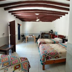 a bedroom with two beds and a table and a ceiling at Posada los abuelos in Holbox Island