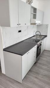 a kitchen with white cabinets and a black counter top at Apartmaji Branko in Renče