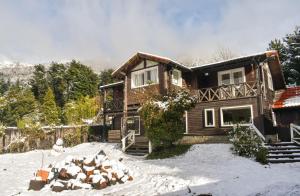 una casa con un montón de nieve delante de ella en INDÓMITO HOSTEL en San Carlos de Bariloche