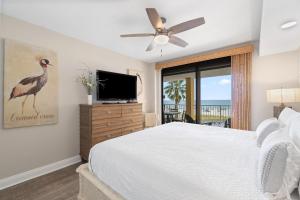 een slaapkamer met een groot bed en een televisie bij Summer House 203A in Orange Beach