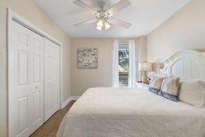 Schlafzimmer mit einem weißen Bett und einem Deckenventilator in der Unterkunft Summer House 203A in Orange Beach