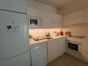 eine weiße Küche mit einer Spüle und einem Kühlschrank in der Unterkunft By Plaza Universidad Rooms in Barcelona